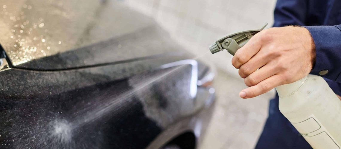Person using spray bottle to clean car with water spots at Pony Express Carwash.